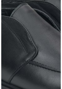 Zwarte leren schoenen hebben een gladde textuur en subtiele stikdetails, met een afgerond ontwerp en elastische zijpanelen voor gemakkelijk aan- en uittrekken.