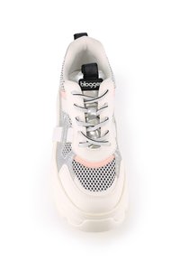 Zapatilla blanca y gris con paneles de malla, acentos en rosa y una suela gruesa. Cuenta con cordones y una lengüeta con marca en el talón.