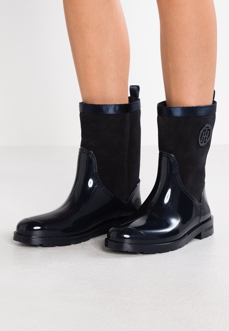 Mustat patenttinahasta ja mokasta tehdyt nilkkurit, joissa on pyöreä kärki, sileä pinta, kiiltävä viimeistely ja sivussa oleva logoyksityiskohta.