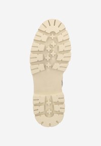 Gummisohle mit strukturierter Oberfläche, die tiefe Profile und sternförmige Muster aufweist. Die Farbe ist offwhite mit mattem Finish.