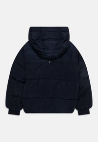 Prošívaná bunda v námořnické modři s kapucí, vybavená prošívaným vzorem, elastickými manžetami a malým logem značky na zádech v blízkosti krku.