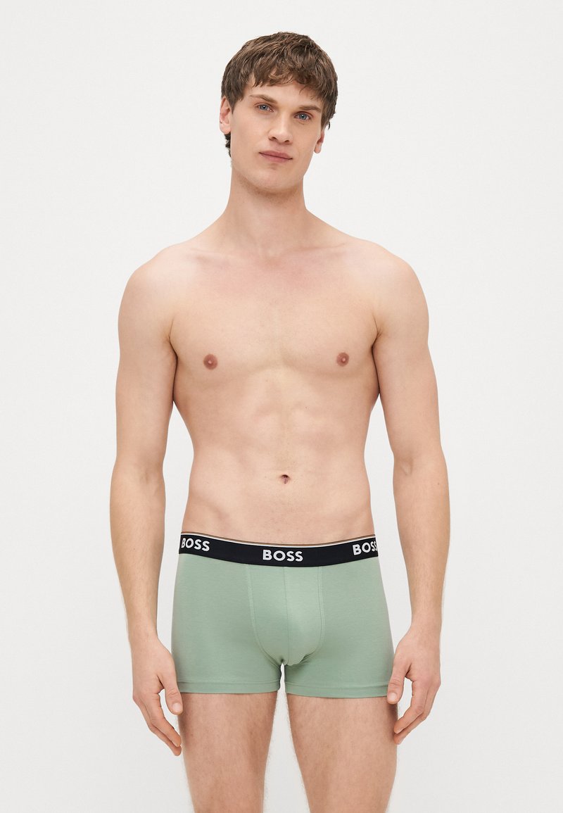 Cuecas boxer de algodão verde com cintura preta apresentando o logótipo "BOSS". Design ajustado ao corpo com textura suave e comprimento até a metade da coxa.