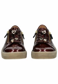Zapatillas de charol burdeos con cremalleras doradas, suelas de color beige texturizado y acentos de hardware en forma de corazón en los cordones.