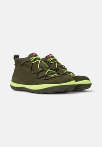 Khaki wysokie buty sportowe z jasnzielonymi sznurowadłami i podeszwami, ustawione obok siebie na białym tle.