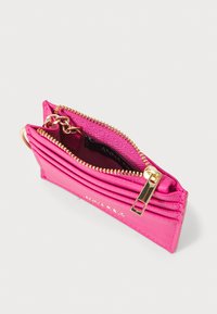 Bright pink wallet made of textured material, featuring a zip closure with gold hardware and multiple card slots. Interior tag visible.