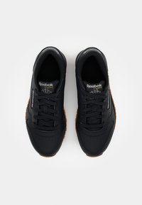 Sorte treningssko med en glatt syntetisk overdel, rund tå og gummisåle. Funksjoner inkluderer snøring og Reebok-logo på tungen.