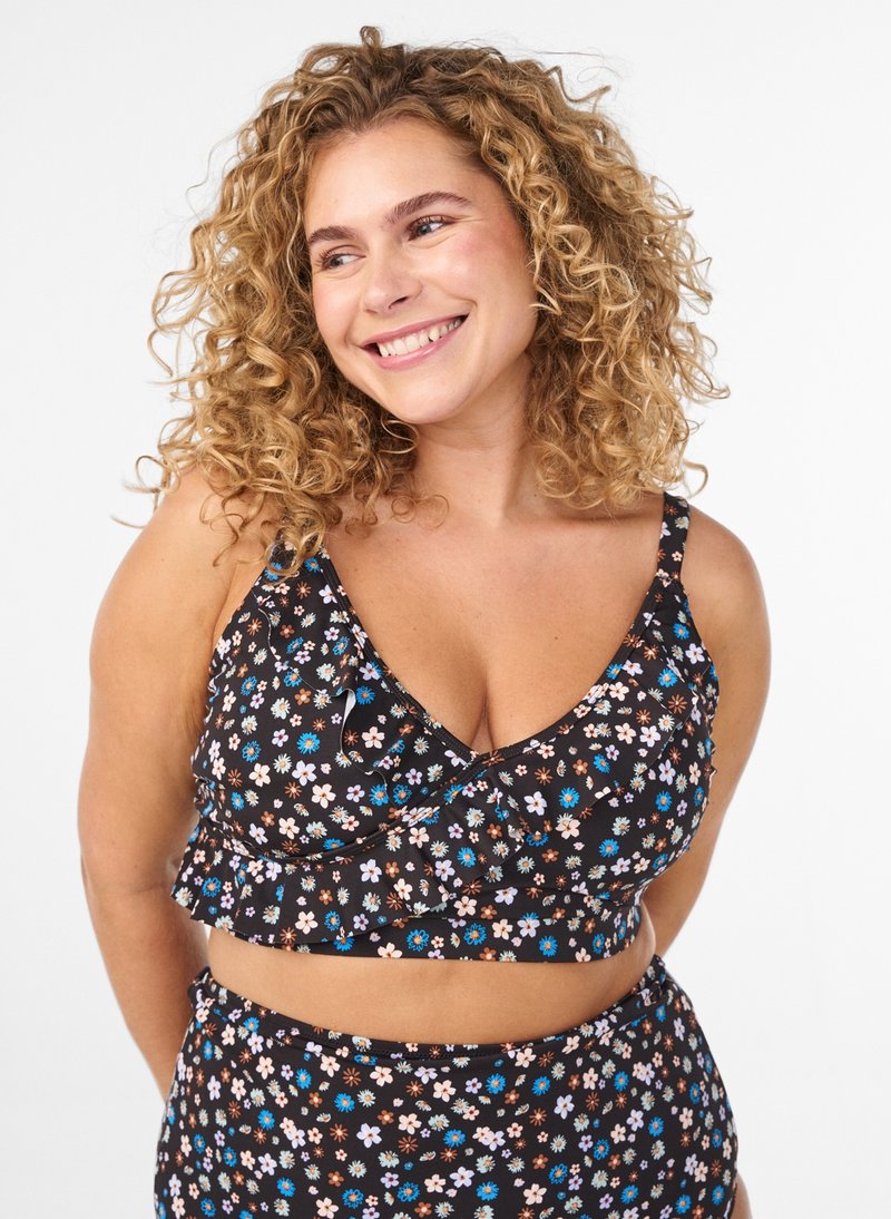Bralette à imprimé floral noir avec ourlet à volants et bretelles réglables, présentant de petites fleurs pastel en bleu, rose et blanc. Bas assorti.