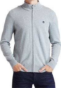 Ljusgrå zip-up cardigan gjord av stickat tyg, med hög krage och ribbade muddar och kant. Har en liten logotyp på bröstet.