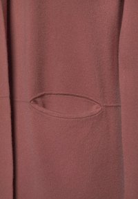 Bordeauxrode sweatshirtstof met een gladde textuur, een ovale zak, geïntegreerd naadontwerp en een ontspannen pasvorm.