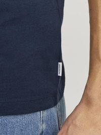 T-shirt en coton bleu marine avec un col rond, des manches courtes et une petite étiquette sur l'ourlet. Texture lisse, coupe décontractée.