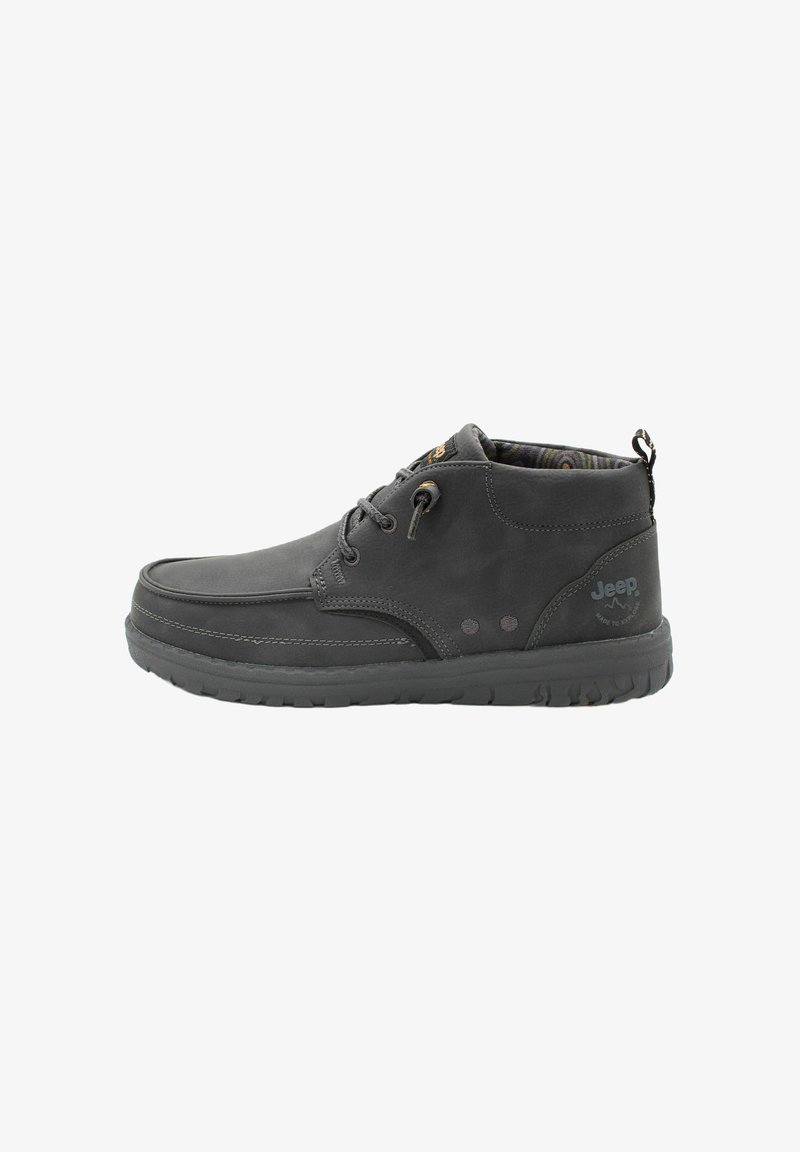 Bottine en cuir noire avec bout rond, lacets à l'avant et semelle en caoutchouc. L'intérieur présente une doublure à rayures colorées. Logo sur le côté.