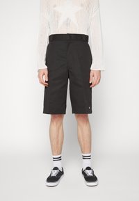 Shorts noirs avec une taille mi-haute et des poches latérales, présentant un design épuré et un petit logo sur la jambe inférieure.