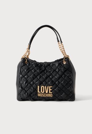 Musta tikattu käsilaukku, jossa kultaiset ketju kahvat ja kultainen "LOVE MOSCHINO" logo edessä, yksinkertaisen vaalean taustan edessä.