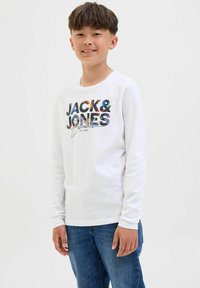 T-shirt bianco a maniche lunghe con grafica testuale multicolore "JACK & JONES" e "Essentials", abbinato a jeans in denim blu.