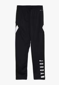 Černé tepláky s bílými akcenty a nápisem "JORDAN" tištěným vertikálně na levé nohavici. Mají elastický pas a hladký povrch.