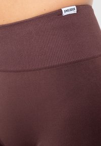 Ruske ribane legice z širokim pasom, ki imajo zgoraj majhno belo oznako. Material se zdi elastičen in gladek.