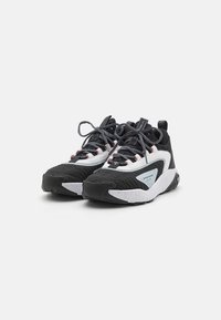 Sorte og hvide sneakers med struktureret sort stof og en glat hvid mellemsål. Har tykke snørebånd og en polstret krave for støtte.