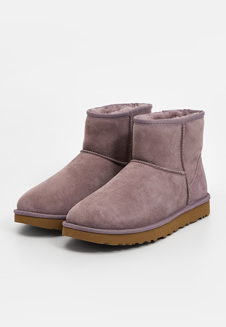 Stivali alla caviglia in suede viola con un morbido rivestimento interno, punta rotonda e suola in gomma. Presentano cuciture semplici e un tacco basso e testurizzato.