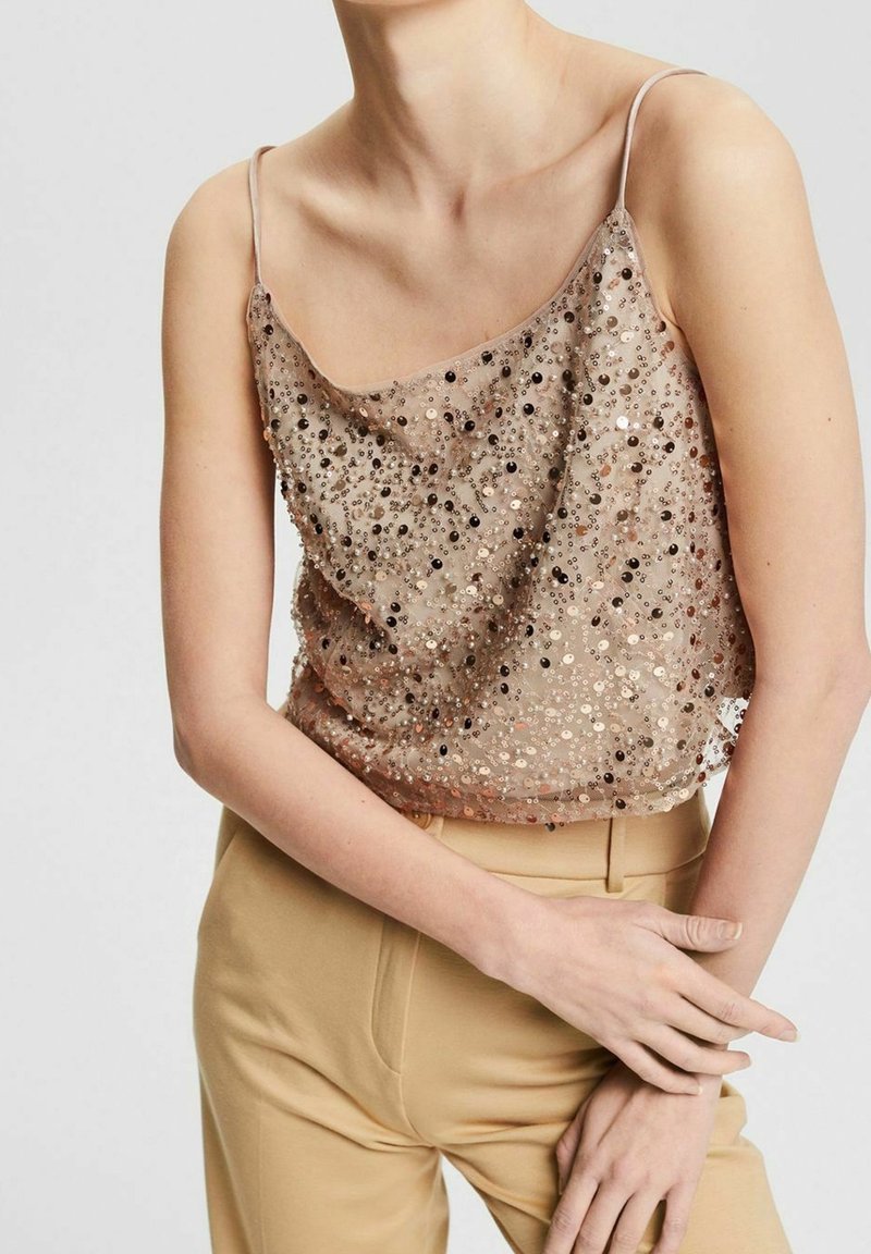 Beige paljettcamisole med tunna band, med en draperad design och olika storlekar på glittrande detaljer. Stylingen kompletteras av hög midja beige byxor.