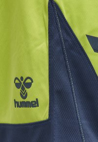 Hummel sportsskjorta med en ljusgrön överdel och marinblå accenter, strukturerad tyg och en logotyp i det nedre vänstra hörnet.