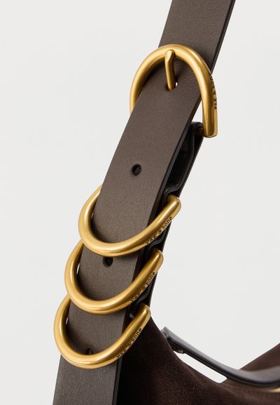 Σκούρος καφέ δερμάτινος ζώνη με τρεις σύγχρονους, χοντρούς χρυσούς μεταλλικούς κρίκους χαραγμένους με την επιγραφή "rag & bone" σε ανοιχτό φόντο.