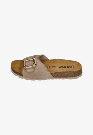 Beige slide sandal made of suede with a large metal buckle, cork footbed, and a textured rubber sole. Features a flat, open design.