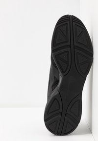 Black athletic shoe with rubber outsole featuring textured triangular patterns and a breathable upper mesh design.