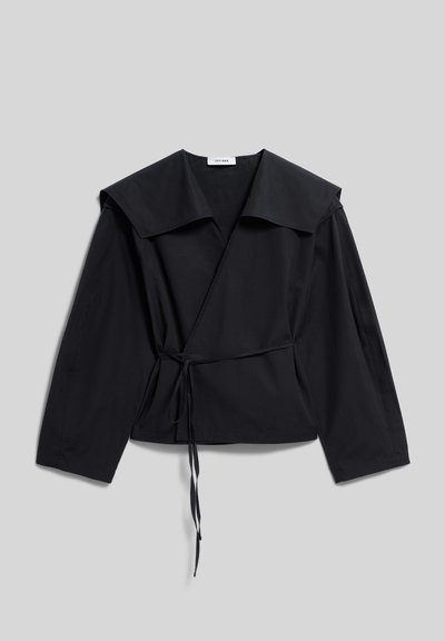 Black long-sleeve wrap blouse with wide collar and tie belt, laid flat on a light gray background.