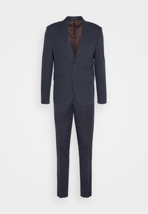 Costume bleu marine foncé avec une veste à un bouton, deux poches, revers à crans et un pantalon à taille plate. Tissu lisse, détail minimal.