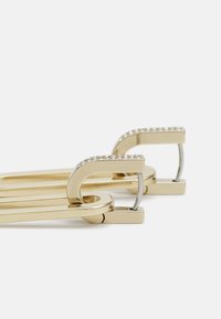 Barrettes dorées avec une forme épurée et allongée, ornées d'une rangée de strass transparents le long du bord supérieur incurvé.