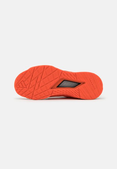 Bright orange athletic shoe sole with a textured surface, featuring a triangular pattern and a black accent near the arch.