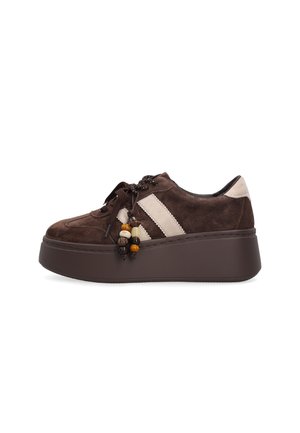 Bruine suède plateau sneaker met dikke zool, beige strepen aan de zijkanten en decoratieve kralen die aan de veters hangen.