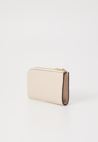 Kompakte beige Geldbörse aus strukturiertem Leder, mit einem goldenen Reißverschluss und kontrastierenden dunklen Kanten, rechteckiger Form und schlankem Profil.