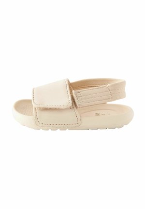 Sandale beige pour tout-petit avec large bride avant et bride arrière élastique, semelle texturée pour une meilleure adhérence, conçue pour un enfilage facile et le confort.