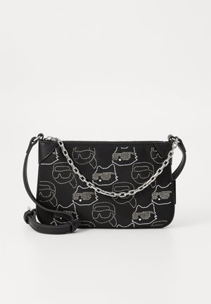 Black crossbody bag with a chain strap, featuring a textured pattern of faces with sunglasses, accented with silver studs. Zipper closure.