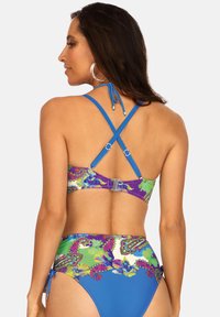Dwuczęściowy kostium bikini z niebieską, gładką górą z krzyżującymi się ramiączkami oraz żywo kwiecistym dołem. Materiał wydaje się gładki o błyszczącej fakturze.