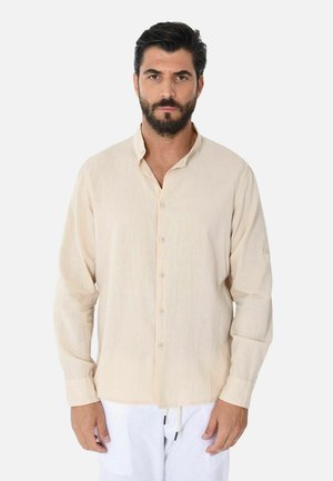 Camicia a maniche lunghe beige realizzata in tessuto leggero, con colletto abbottonato, caratterizzata da una vestibilità rilassata e maniche arrotolabili.