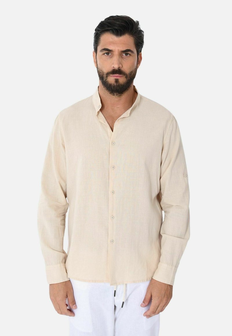 Camicia a maniche lunghe beige realizzata in tessuto leggero, con colletto abbottonato, caratterizzata da una vestibilità rilassata e maniche arrotolabili.