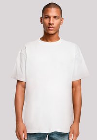Weißes Baumwoll-T-Shirt mit Rundhalsausschnitt, kurzen Ärmeln und lockerer Passform. Glatte Textur und minimales Design ohne Verzierungen.