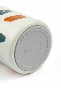 Ceramiczny kubek o białej podstawie, ozdobiony abstrakcyjnymi kształtami w kolorze zielonym, pomarańczowym i niebieskim. Na dnie znajduje się szare, wypukłe instrukcje dotyczące pielęgnacji.