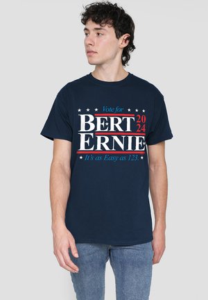 Navy blue cotton t-shirt featuring bold white and red text reading "Vote for BERT 2024 ERNIE" with blue accents and star motifs.