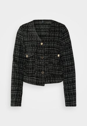 Fekete-fehér kockás dzseki, amelynek rövidített fazonja van, arany gombokkal, két elülső zsebbel és texturált anyagból készült.