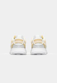 Chaussures de sport avec une tige principalement en mesh blanc et des accents jaunes ; design arrondi avec un col rembourré et une semelle texturée.