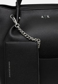 Borsa a mano in pelle nera con texture granitata, hardware in metallo argentato e pochette rimovibile con zip caratterizzata dal logo "Armani Exchange".