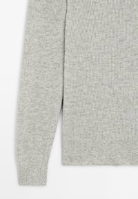 Grauer Rippstrickpullover mit strukturierter Oberfläche, langen Ärmeln und tailliertem Bund. Das Material wirkt weich und gestrickt.