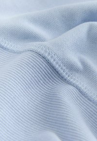 Šviesiai mėlyna medžiaga su lygiu paviršiumi, kurioje matyti plonos briaunuotos linijos ir siūlės palei kraštus, suteikiančios minkštą, laisvai krentančią išvaizdą.