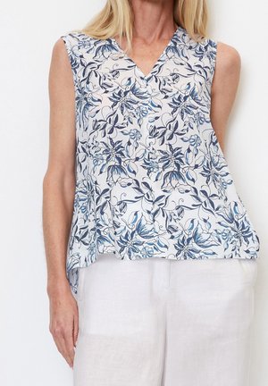 Ärmelloses Blusenshirt mit floralem Muster in Blau und Weiß, V-Ausschnitt und fließendem Stoff, kombiniert mit hellen Hosen.