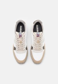 Sneaker con una toma superiore in tessuto bianco, dettagli in suede beige, sovrapposizioni marroni e lacci di colore chiaro. Presenta un'etichetta con logo e un dettaglio a forma di bandiera.