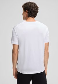 Witte katoen T-shirt met korte mouwen, ronde hals en rechte snit. Achteraanzicht toont een gladde textuur en een minimaal ontwerp.