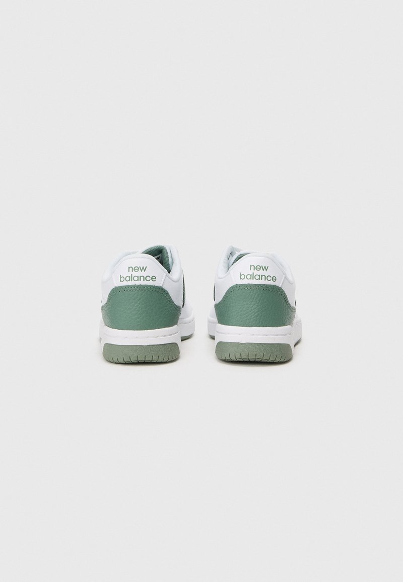Zapatillas verdes y blancas con un dorso de cuero texturizado, que presentan un cuello acolchado y el logo de "new balance" en el talón. Suela de goma.